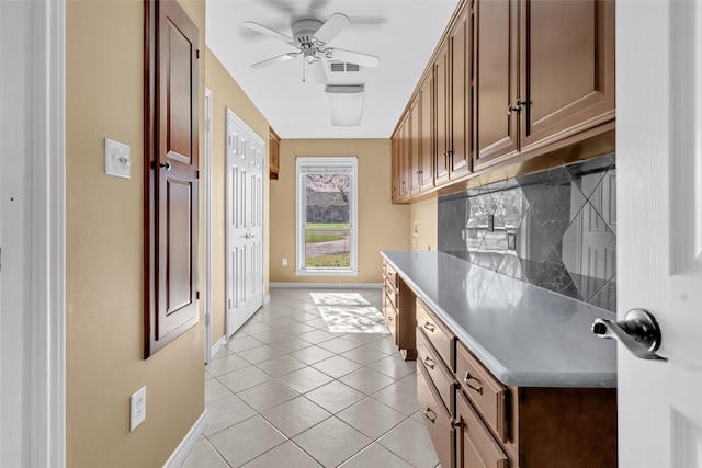 kitchen with decorative backsplash, light tile patterned floors, built in desk, and ceiling fan