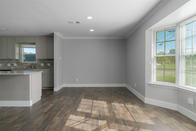 kitchen with light stone countertops, backsplash, ornamental molding, gray cabinets, and dark hardwood / wood-style floors