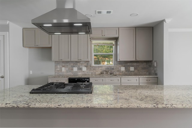 kitchen featuring gray cabinets, ventilation hood, light stone counters, and backsplash