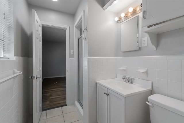 bathroom with walk in shower, hardwood / wood-style floors, toilet, vanity, and tile walls