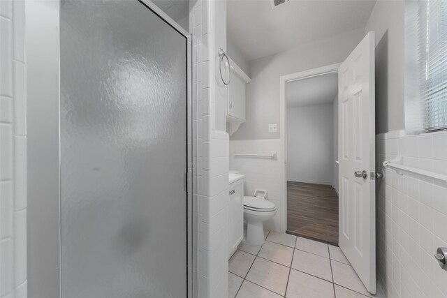 bathroom featuring vanity, tile patterned flooring, toilet, tile walls, and walk in shower