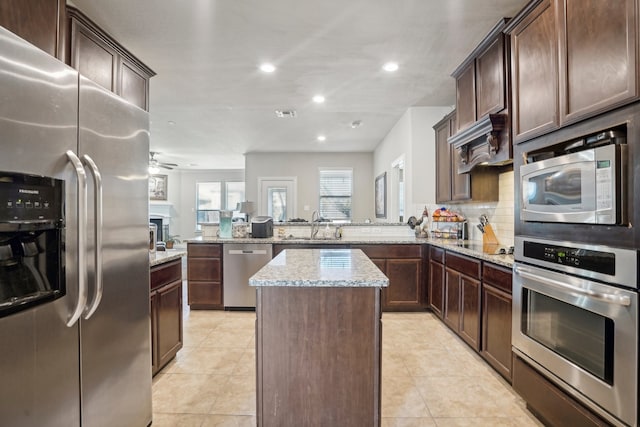 kitchen with a center island, light stone counters, kitchen peninsula, and stainless steel appliances