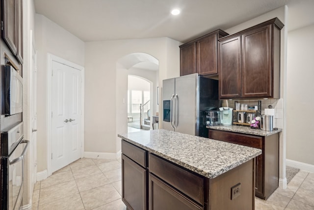 kitchen with dark brown cabinets, a kitchen island, decorative backsplash, and stainless steel appliances