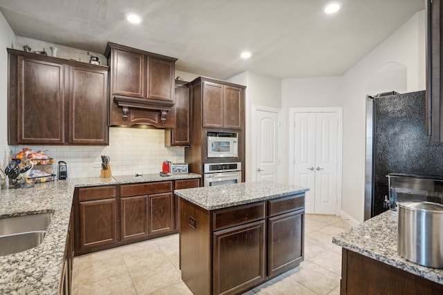 kitchen with a center island, light stone countertops, and appliances with stainless steel finishes