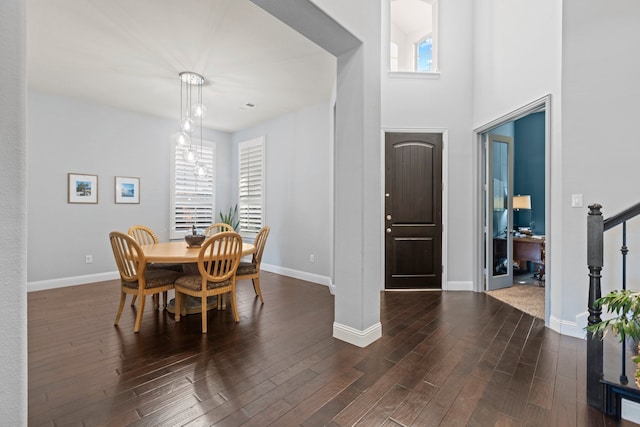 dining space featuring dark wood finished floors, baseboards, and stairs