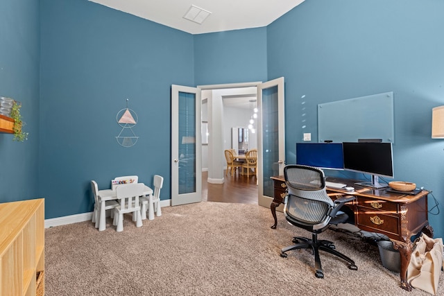 carpeted office space featuring french doors, visible vents, and baseboards