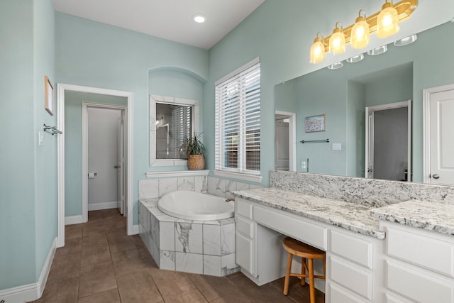 bathroom with vanity, a bath, and baseboards