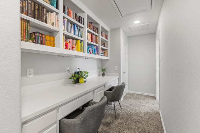 office area with carpet flooring, visible vents, baseboards, built in desk, and attic access