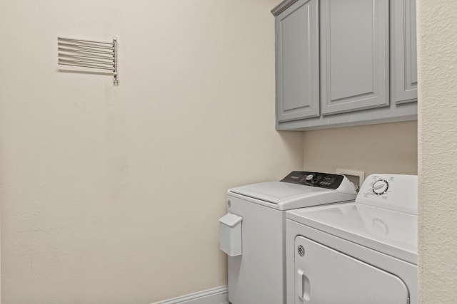 laundry area with washing machine and dryer, cabinet space, and baseboards