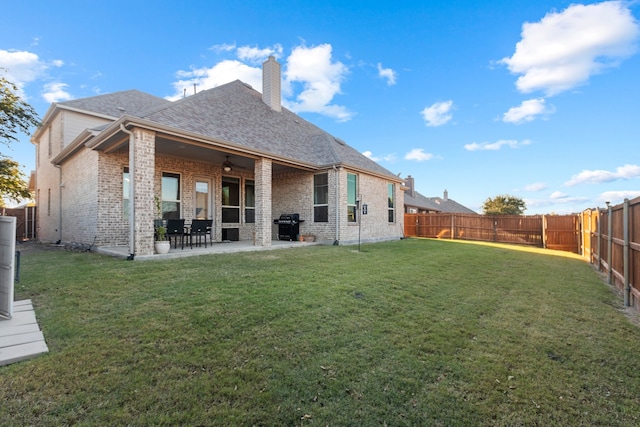 rear view of house with ceiling fan, a patio, brick siding, and a fenced backyard