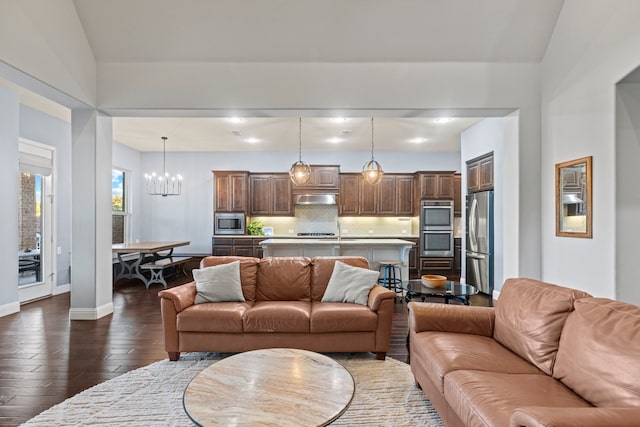 living area featuring dark wood-style flooring, a notable chandelier, and baseboards