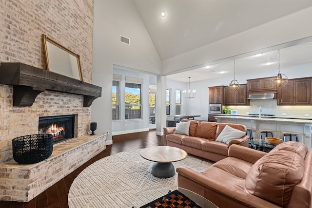 living area featuring dark wood-style flooring, visible vents, a brick fireplace, high vaulted ceiling, and baseboards