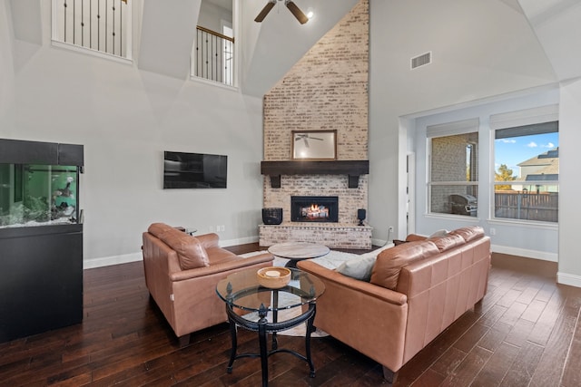 living room featuring dark wood-type flooring, ceiling fan, high vaulted ceiling, and a brick fireplace