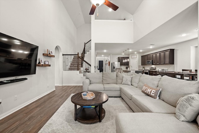 living room with sink, a towering ceiling, ceiling fan, and wood-type flooring