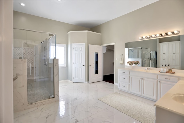 bathroom with marble finish floor, a marble finish shower, a spacious closet, vanity, and baseboards