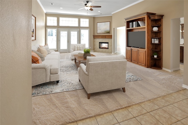 living room with crown molding, ceiling fan, a fireplace, and light tile patterned floors