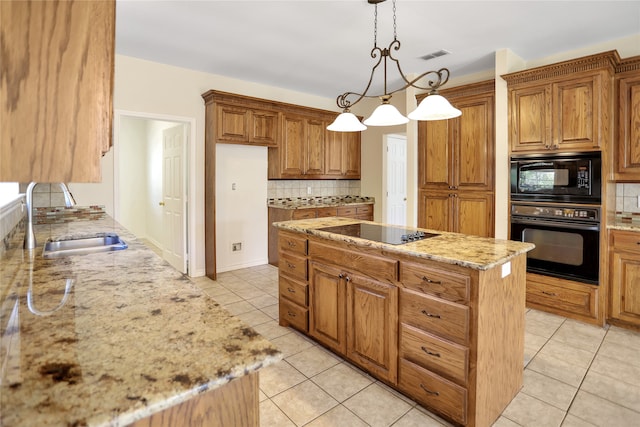 kitchen featuring a kitchen island, a sink, hanging light fixtures, light stone countertops, and black appliances