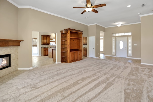 unfurnished living room featuring ornamental molding, a tile fireplace, and light carpet