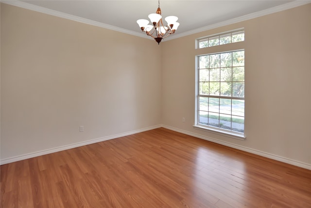 empty room featuring a notable chandelier, wood-type flooring, and ornamental molding