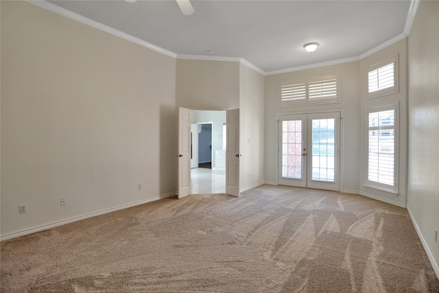 unfurnished room featuring crown molding, a towering ceiling, light carpet, and french doors