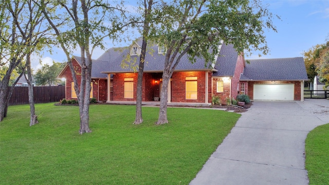 view of front facade with brick siding, concrete driveway, fence, a garage, and a front lawn