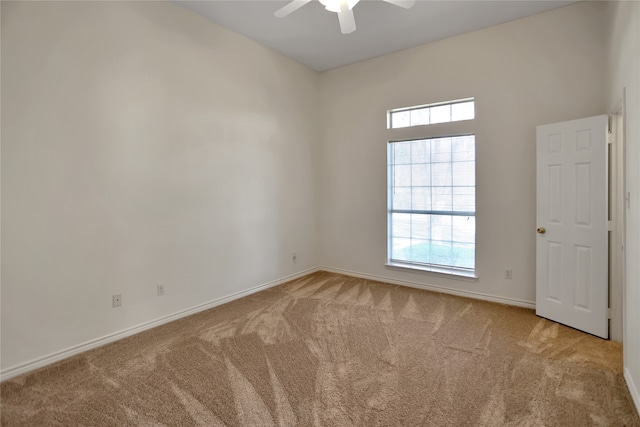 spare room with ceiling fan, baseboards, and light colored carpet