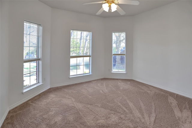 carpeted spare room featuring plenty of natural light, baseboards, and ceiling fan