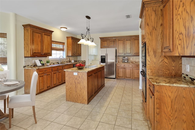 kitchen with hanging light fixtures, a kitchen island, stainless steel refrigerator with ice dispenser, and light stone countertops