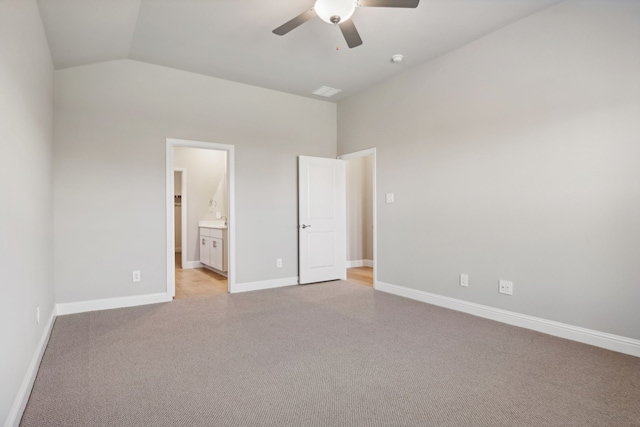 unfurnished bedroom featuring lofted ceiling, connected bathroom, light colored carpet, and ceiling fan