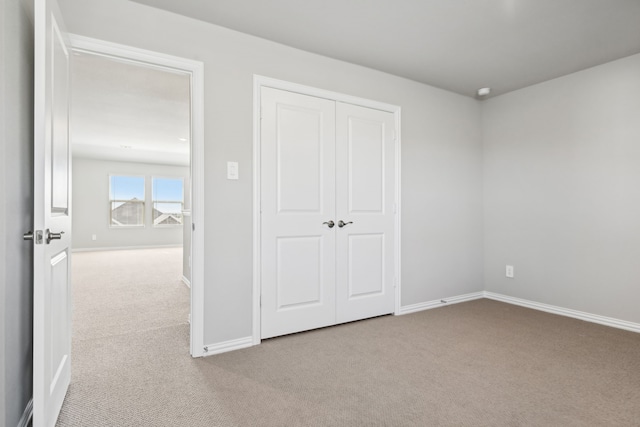 unfurnished bedroom with light colored carpet and a closet