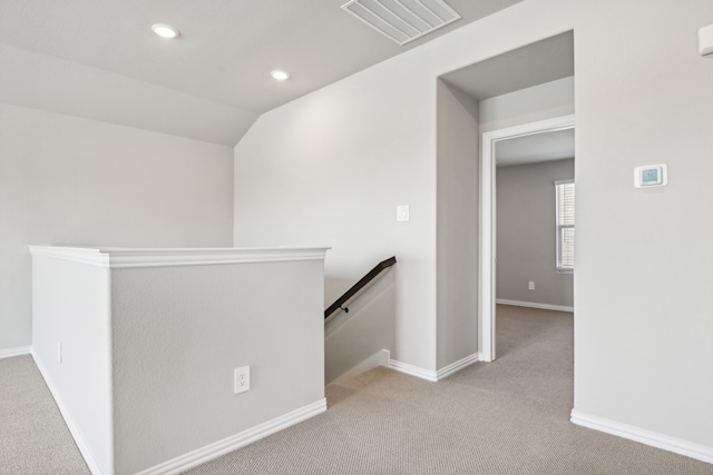 corridor featuring lofted ceiling and light carpet