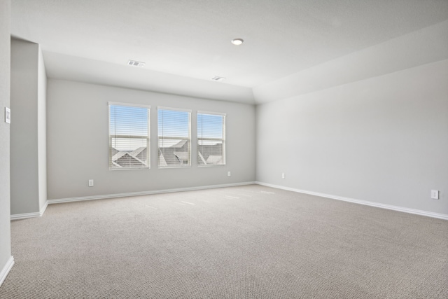 carpeted empty room featuring vaulted ceiling