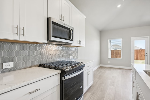 kitchen featuring backsplash, white cabinets, black gas stove, light hardwood / wood-style flooring, and light stone countertops