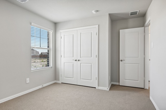 unfurnished bedroom with light carpet and a closet