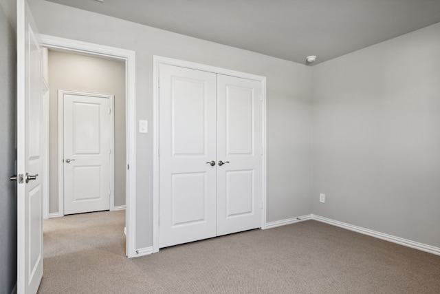 unfurnished bedroom featuring light colored carpet and a closet