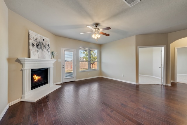 unfurnished living room with ceiling fan, dark wood-type flooring, and a textured ceiling