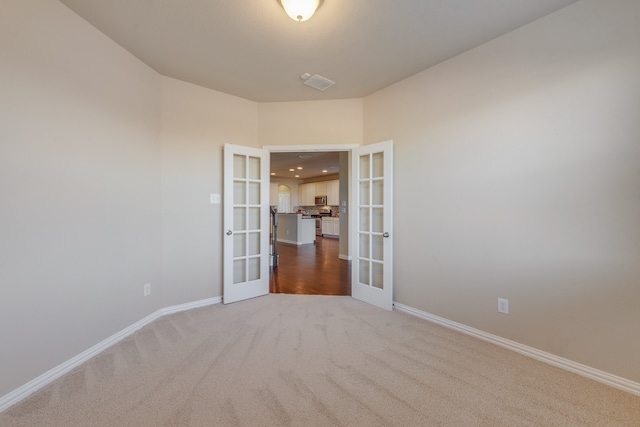 carpeted spare room featuring french doors