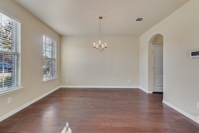 unfurnished room featuring a notable chandelier and dark hardwood / wood-style flooring