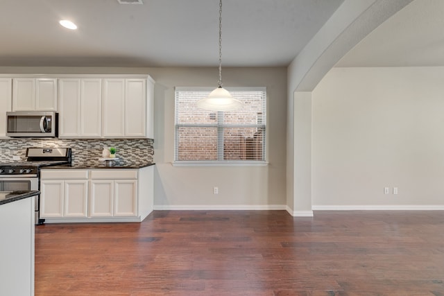 kitchen featuring pendant lighting, decorative backsplash, white cabinetry, and appliances with stainless steel finishes