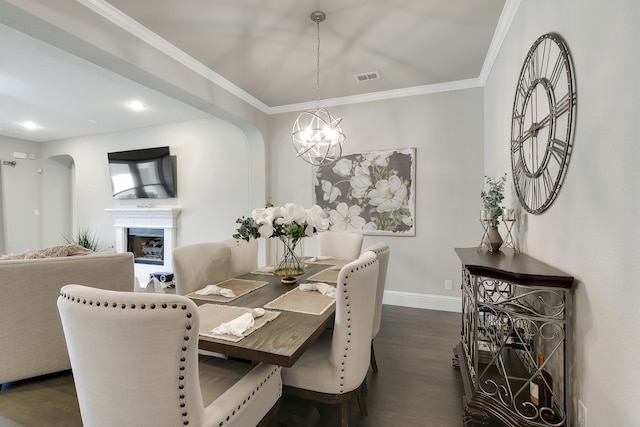 dining area with crown molding, dark hardwood / wood-style floors, and an inviting chandelier