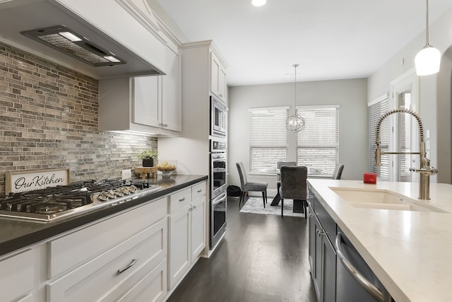 kitchen with hanging light fixtures, premium range hood, white cabinets, and stainless steel appliances