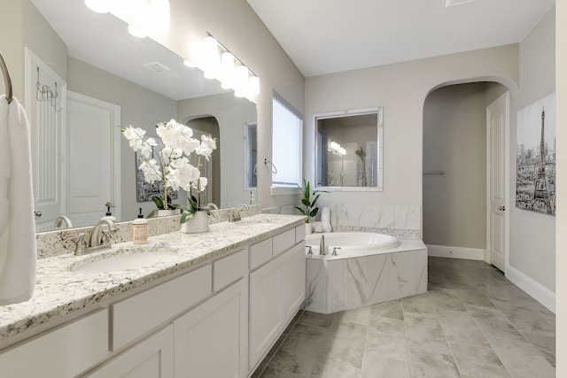 bathroom featuring a relaxing tiled tub and vanity