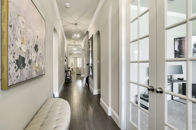 corridor featuring a notable chandelier, ornamental molding, dark wood-type flooring, and french doors