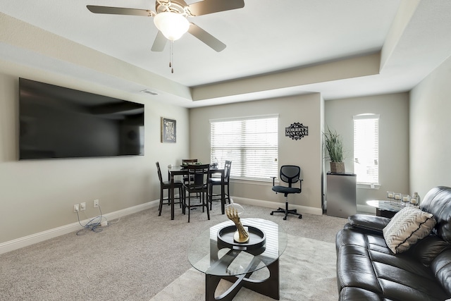 carpeted living room featuring a tray ceiling and ceiling fan