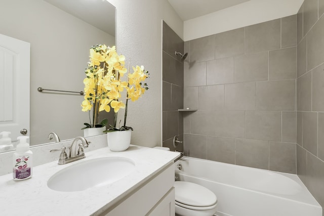 full bathroom featuring tiled shower / bath, vanity, and toilet