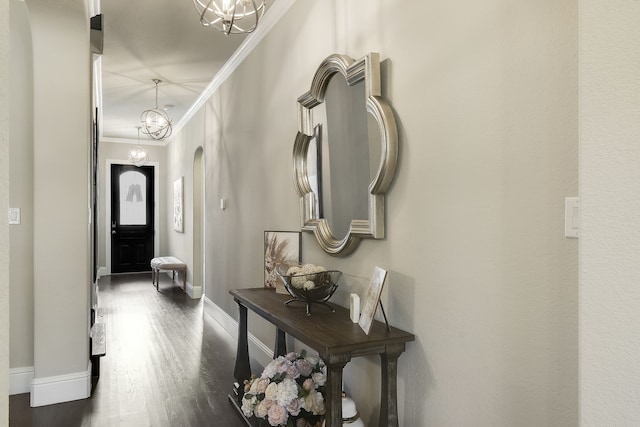 foyer entrance with dark hardwood / wood-style flooring, an inviting chandelier, and ornamental molding