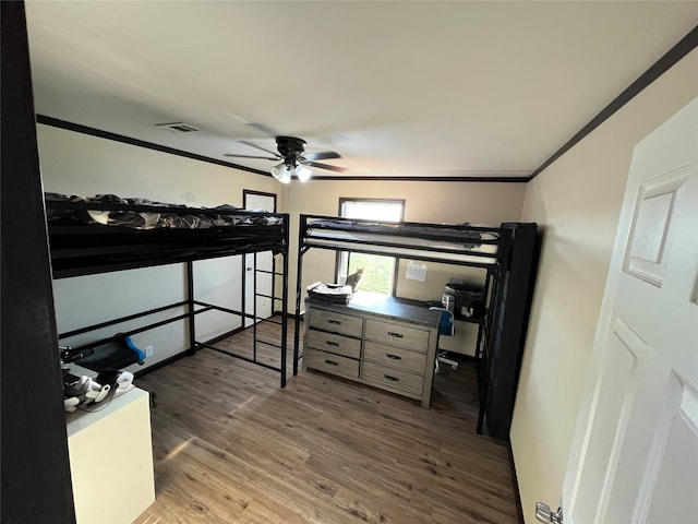 bedroom with ceiling fan, dark hardwood / wood-style flooring, and ornamental molding