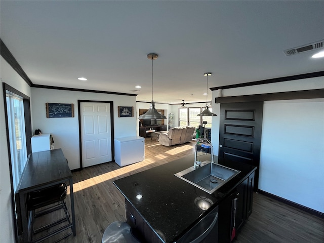 kitchen with pendant lighting, a wood stove, sink, a kitchen island, and dark hardwood / wood-style flooring