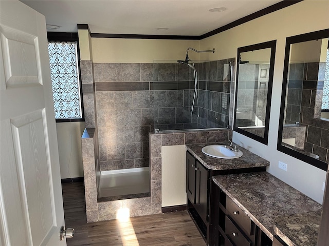 bathroom with hardwood / wood-style floors, tiled shower, crown molding, and vanity