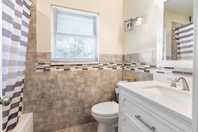 bathroom with vanity, toilet, and tile walls